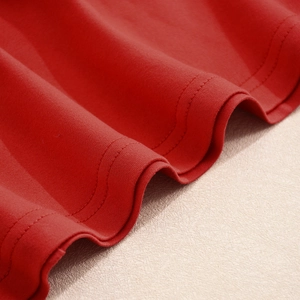 Détail du tissu en maille rouge montrant la couture à double aiguille de la robe