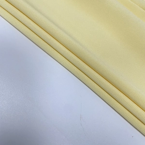 Detailed macro view of soft pale yellow ribbed knit fabric texture on a slim fit dress