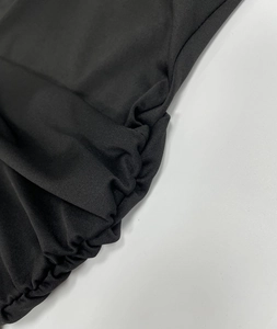 Close-up detail of the black ruched fabric and tight pleats on a bodycon dress