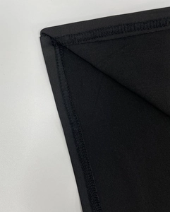 Macro shot of double-needle stitching detail on black ruched bodycon dress