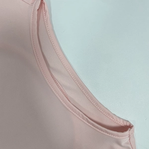 Dettaglio macro dello scollo rotondo con doppia cucitura piatta su un abito rosa pastello