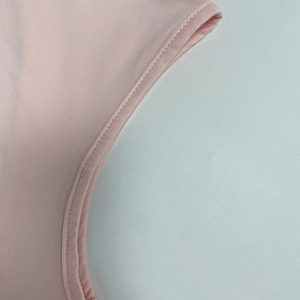 Dettaglio delle cuciture sui bordi di un abito lungo rosa plissettato con schiena scoperta