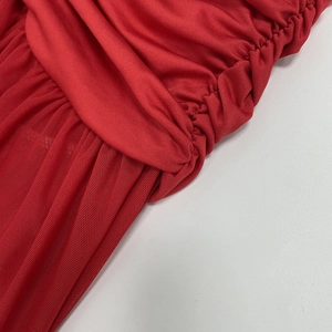 Macro shot of red ruched dress detailing fine mesh texture and layered knit fabric