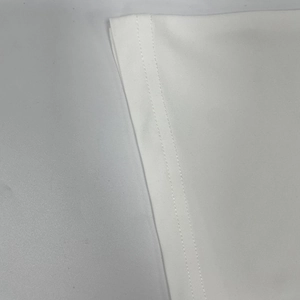 Detailed close-up showing high-quality double-row stitching on white knit dress cuff