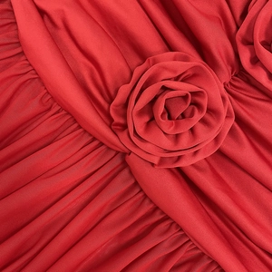 Macro detail of red ruched mesh fabric featuring a 3D handcrafted rose floral appliqué