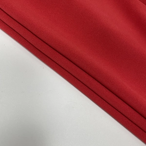 Detail of red ribbed knit fabric texture on a long sleeve off-shoulder dress