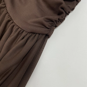 Close-up of brown ruched mesh fabric stitched with plain knit material on the dress