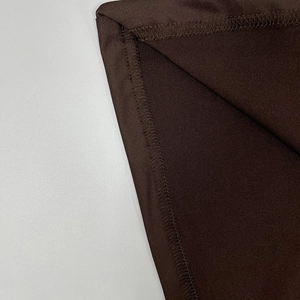 Dettaglio delle cuciture overlock e del tessuto a maglia marrone scuro sull'abito a pieghe