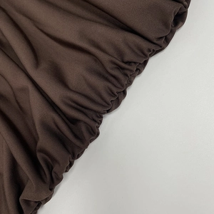 Detail of dark brown ruched fabric showing elegant pleated texture and premium stitching