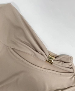 Vue macro détaillée de la boucle en métal doré en V sur la robe plissée beige