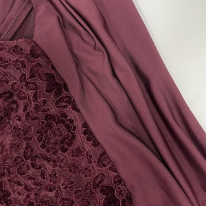 Détail en gros plan du velours dentelle bordeaux et du tissu plissé d'une robe de soirée