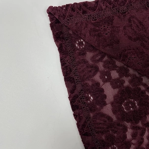 Gros plan sur le tissu en dentelle bordeaux avec texture florale et détails de couture