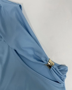 Gros plan détaillé d'une robe côtelée bleu clair avec une boucle en métal doré en forme de V
