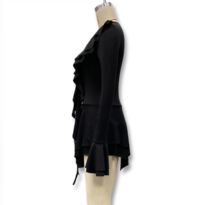 Détail des volants superposés sur une robe noire à manches longues et coupe ajustée