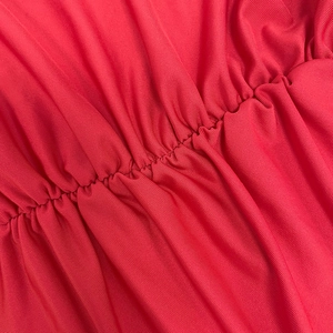 Détail du tissu élastique rouge avec texture froncée et reflets subtils