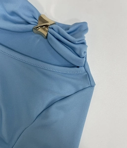 Détail du tissu en maille bleu clair avec une boucle décorative en métal doré en V