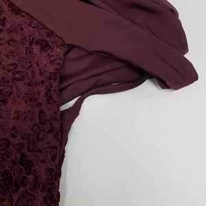Vue détaillée de la robe bordeaux avec tissu élastique lisse et texture en dentelle florale
