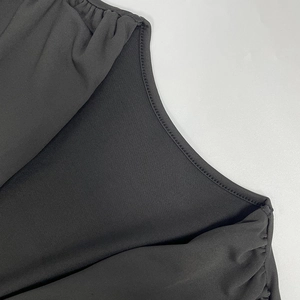 Détail de l'encolure froncée et de la texture du tissu de qualité de la robe noire moulante