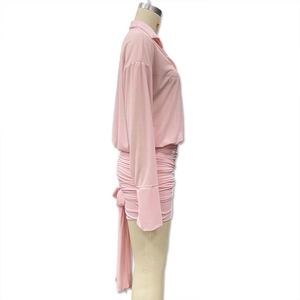 Detail view of pink long sleeve mini dress featuring side ruched fabric and back tie ribbon