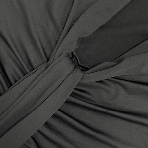 Détail d'une robe noire élégante montrant le nœud torsadé et la texture du tissu plissé
