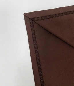 Close-up of chocolate brown fabric showing professional four-thread overlock seam detail