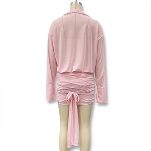 Detail of pink long-sleeve ruched dress with decorative bow tie and slim fit design