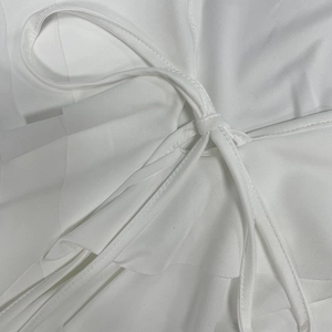 Gros plan d'une robe blanche avec volants superposés et détail de lien délicat en tissu