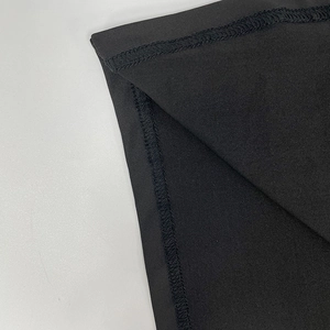 Détail du point plat et du surjet soigné sur le tissu en maille noire de la robe