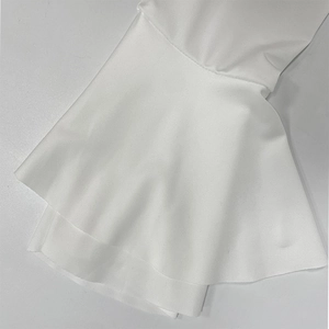 Détail macro des poignets à volants blancs et du tissu texturé de la robe à col en V