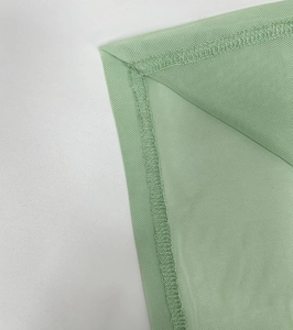 Close-up of overlock stitching and seams on mint green ruched backless dress fabric