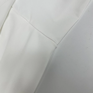 Vue macro détaillée du tissu d'une robe blanche montrant les coutures professionnelles