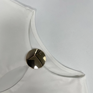 Detail of white knit dress neckline with a large polished gold metal buckle accent