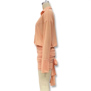 Detail view of apricot long sleeve dress featuring ruched skirt side ties and shirt collar