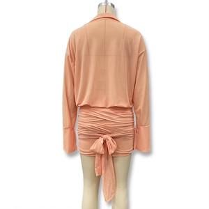 Detail showing the peach-colored dress back with a large bow and elegant ruched texture
