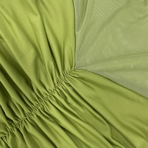 Detailaufnahme von grünem Raffstoff und halbdurchsichtigem Mesh-Einsatz am Kleid