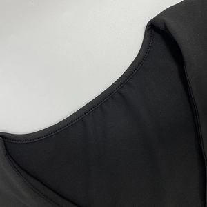 Détail du col en U profond avec couture double aiguille précise sur tissu noir épais