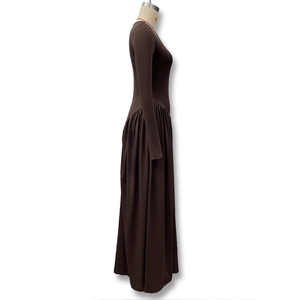 Detail of the elegant ruched high waist and flowing hem on the long brown dress