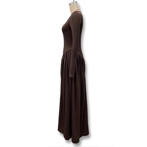 Side view of brown long sleeve maxi dress with cinched high waist and flowing pleated skirt