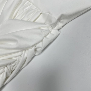 Detailed view of the white dress showing the twisted knot and ruched fabric design