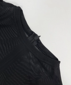 Detail showing the sheer black mesh fabric with a round neck and rear zipper closure