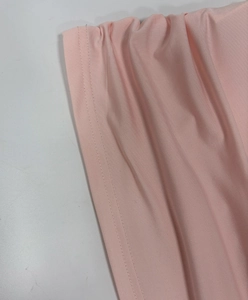 Close-up detail of soft pink elastic fabric with high-quality double-row stitching detail