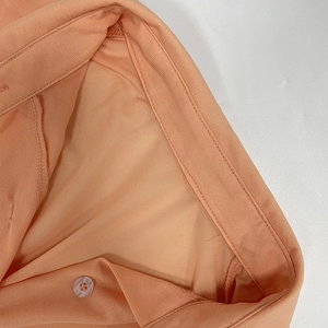 Close-up of the orange shirt collar with matching buttons and fine stitching details