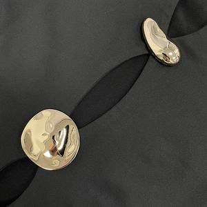 Macro detail of artistic gold buckles and stylish cutout on a black dress fabric