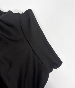 Detail shot of the fine knit texture and high-quality stitching on a black dress sleeve