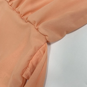 Detail of the elastic pleated waist and seamless side pocket on the apricot dress