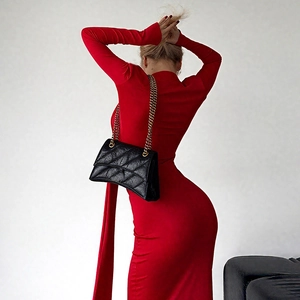 Détail du sac bandoulière en cuir matelassé noir avec chaîne dorée sur robe rouge