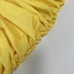 Detailaufnahme des gelben Kleiderstoffs mit elastischer Raffung und Rippenstruktur