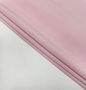 Close-up of pink knitted fabric texture showing pleated details and soft material