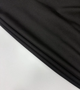 Detail of high-density black knit fabric showing texture and wrinkle resistance on the dress