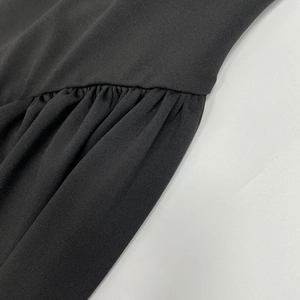 Detailed close-up of the pleated design and soft knit fabric on a black maxi dress